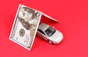 A car model in a shelter made from a 100 dollar bill.