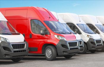 Red delivery van in a row of white vans.