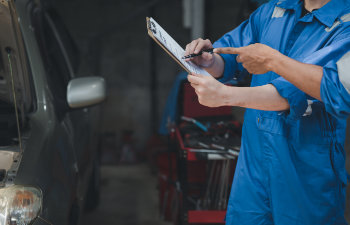 two professional car mechanics looking at car inspection papers together