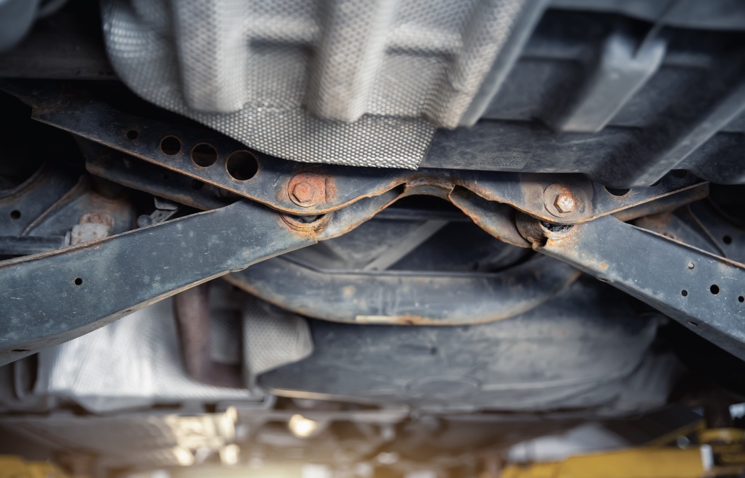 Close-up detail view of bottom car part with rusty broken suspension arm part need replacemant service or maintenance. Vehicle chassis stain warranty repair. Automotive mechanic industrial backround