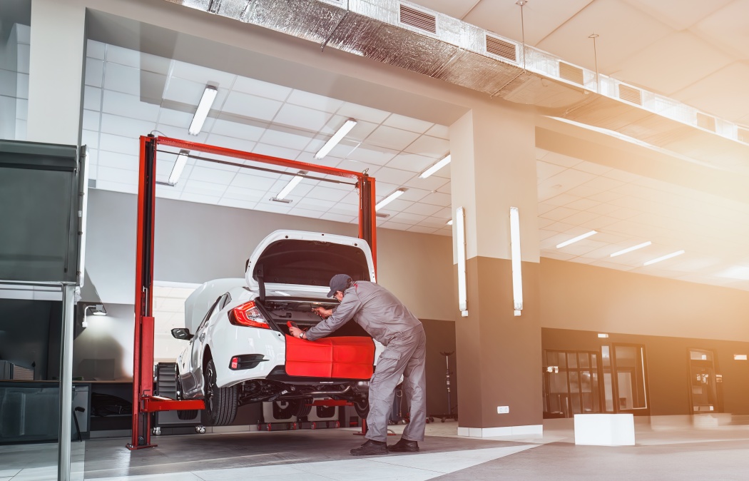 Professional car service. Comprehensive Car Care. Panoramic View of Dealership Service with Mechanic Repairing a Modern Sedan Car. Car shop.